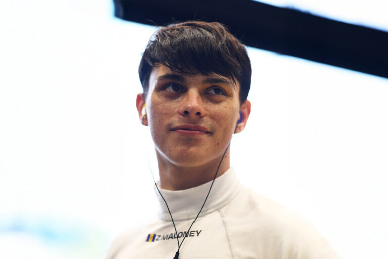 Zane Maloney smiling wearing a white undershirt with his ear pieces in.